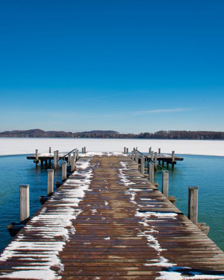 Der Wörthsee, bedeckt mit einer dünnen Eisschicht bei strahlendem Sonnenschein