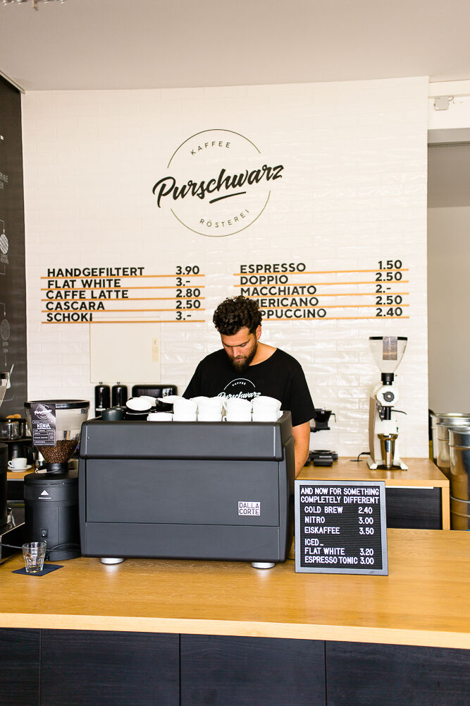Alexander Gourgius steht am Tresen seiner Kaffeebar und bereitet einen Kaffee zu