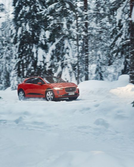Der rote Jaguar I-Pace im schneebedeckten Wald Finnlands
