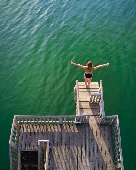 Iris Schmidbauer mit ausgebreiteten Armen auf dem Sprungturm und über dem Ammersee in Utting