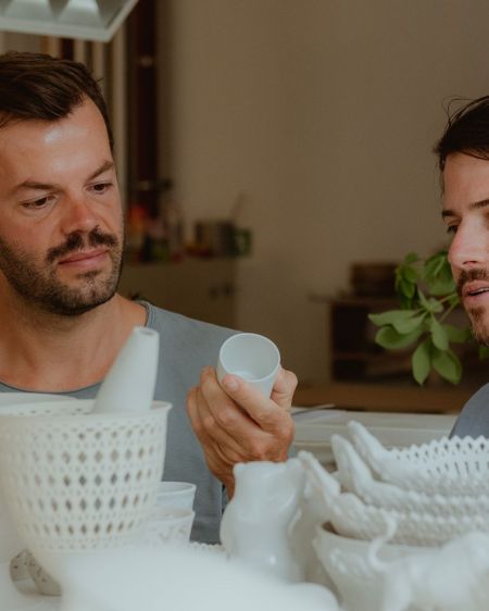 Zwei Männer schauen sich Porzellangeschirr der Königlichen-Porzellan-Manufaktur in Berlin an