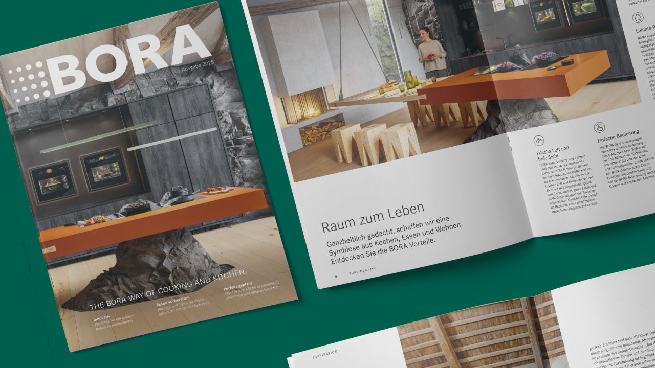 Cover of BORA Magazine issue 2025 next to an open double page spread showing a modern kitchen with an orange cooking island Cover of BORA Magazine issue 2025 next to an open double page spread showing a modern kitchen with an orange cooking island