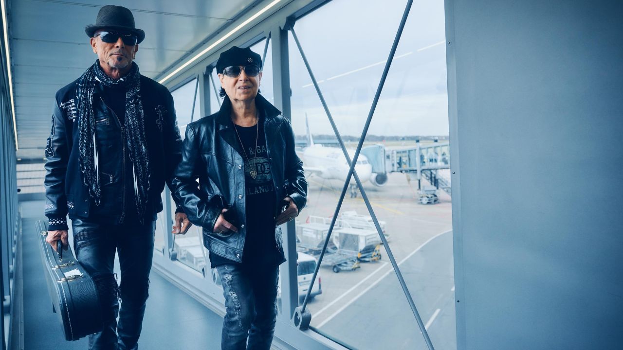 Zwei Mitglieder der Band Scorpions in schwarzen Lederjacken und Sonnenbrillen gehen über Gangway am Flughafen Zwei Mitglieder der Band Scorpions in schwarzen Lederjacken und Sonnenbrillen gehen über Gangway am Flughafen