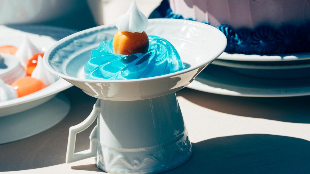 Close-up of a plate with blue jelly and a fruit, standing on an upside-down cup. Close-up of a plate with blue jelly and a fruit, standing on an upside-down cup.
