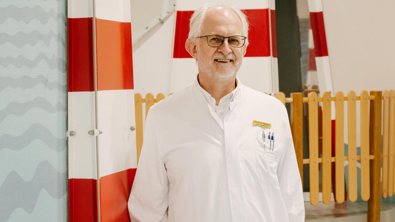 Portrait of an older man in a white doctor's coat, smiling in front of a maritime backdrop Portrait of an older man in a white doctor's coat, smiling in front of a maritime backdrop