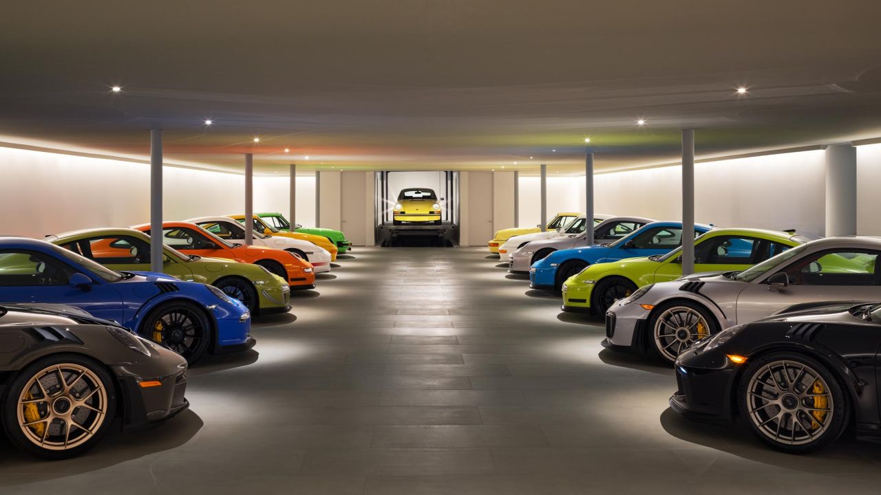 A large collection of colorful Porsche sports cars is lined up in a modern garage. A large collection of colorful Porsche sports cars is lined up in a modern garage.